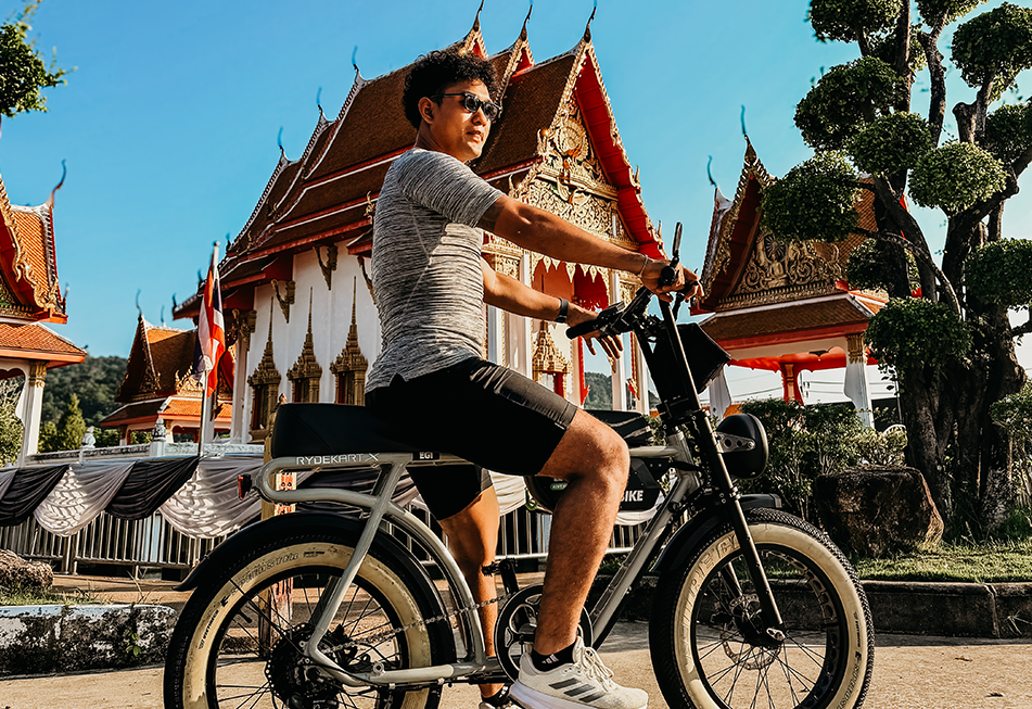 Youg sporty Guy riding a Earl Grey Ebike front of a Thai Buddhist Temple